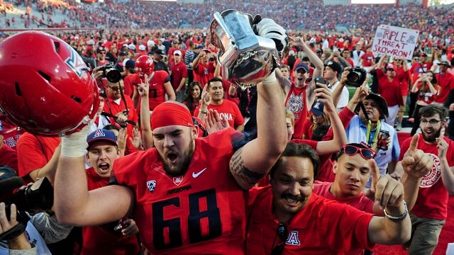Arizona Wildcats offensive lineman Mickey Baucus (68) hoists the territorial cup in celebration after beating the Arizona State Sun Devils 42-35 at Arizona Stadium